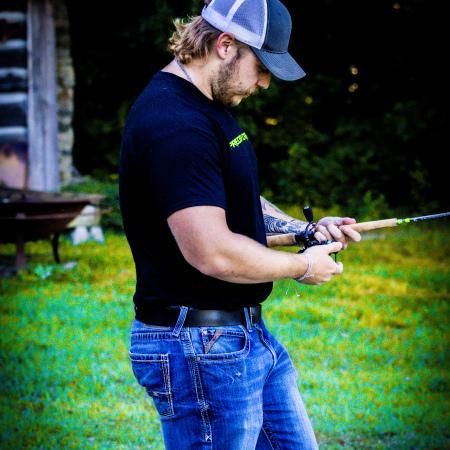 Catch The Fever Marketing Director Dillon Weaver holding a Precision Crappie™ fishing rod while wearing a black Precision Crappie t-shirt with green logo and a Catch The Fever hat.